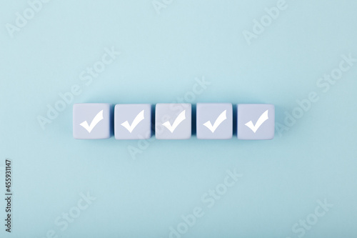 Five checkmarks on white cubes against bright pastel blue background with copy space. Concept of questionary, checklist, to do list, planning, business or verification. Creative minimal composition 