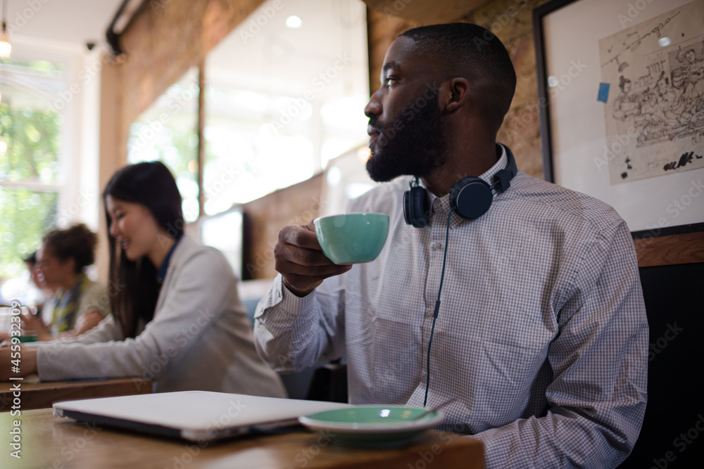 Fototapeta premium Young man with headphones drinking coffee in cafe