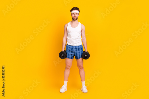 Full length body size view of attractive cheery guy lifting weight doing work out isolated over bright yellow color background