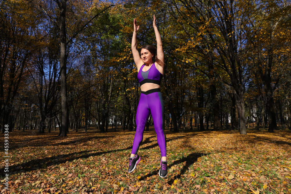 A girl with a tracksuit jumps in the park. Exercise in the fresh air A girl with a tracksuit jumps in the park. Exercise in the fresh air