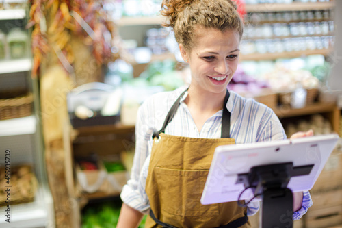 Fényképezés Female cashier using touch screen cash register in grocery store