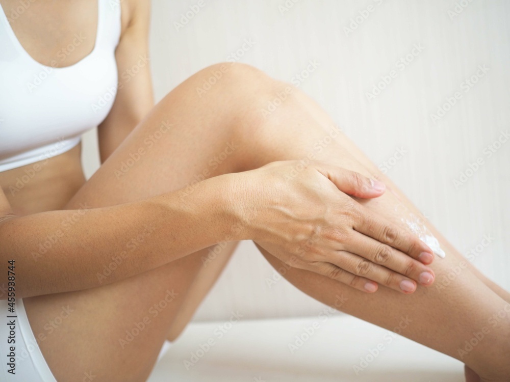 Fototapeta premium Young woman applying body cream at home. the concept of body lotion and health. closeup photo, blurred.