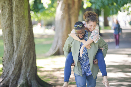 Playful young couple piggybacking in park