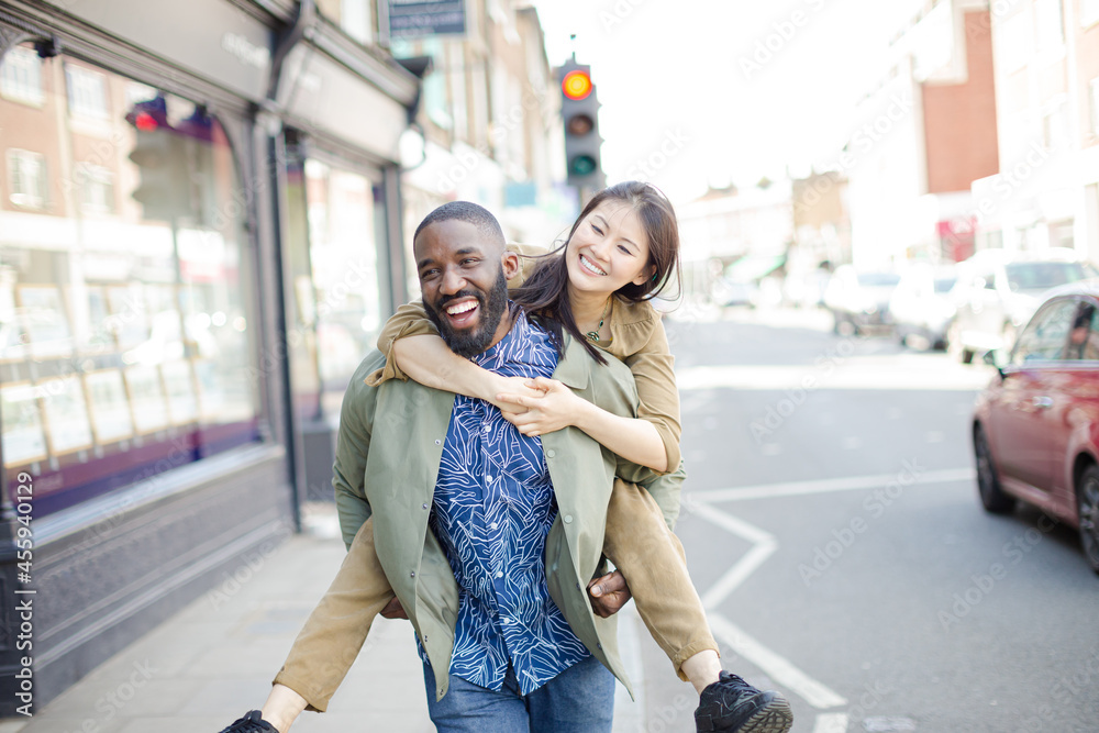 Playful young couple piggybacking on urban street Playful young couple piggybacking on urban street