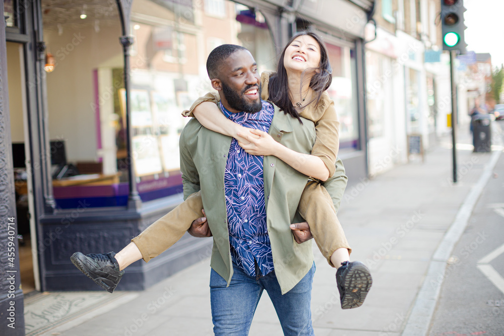 Playful young couple piggybacking on urban street Playful young couple piggybacking on urban street