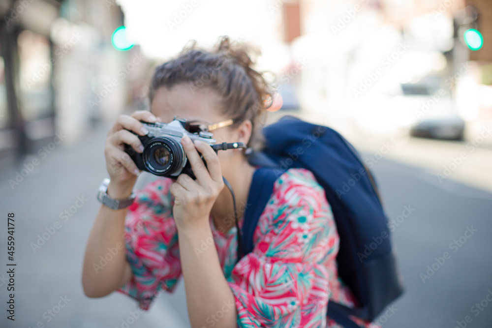 Portrait laughing, enthusiastic young female tourist in sunglasses photographing with camera on urban street