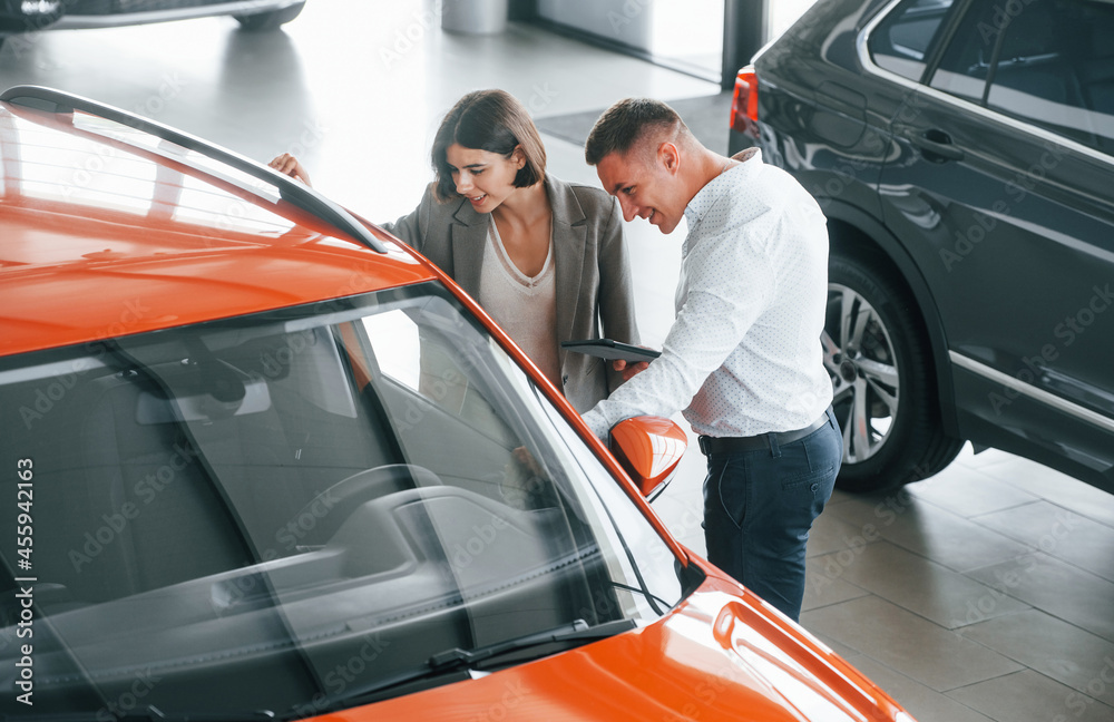 View from above. Man in formal wear helping customer with choice of the automobile View from above. Man in formal wear helping customer with choice of the automobile