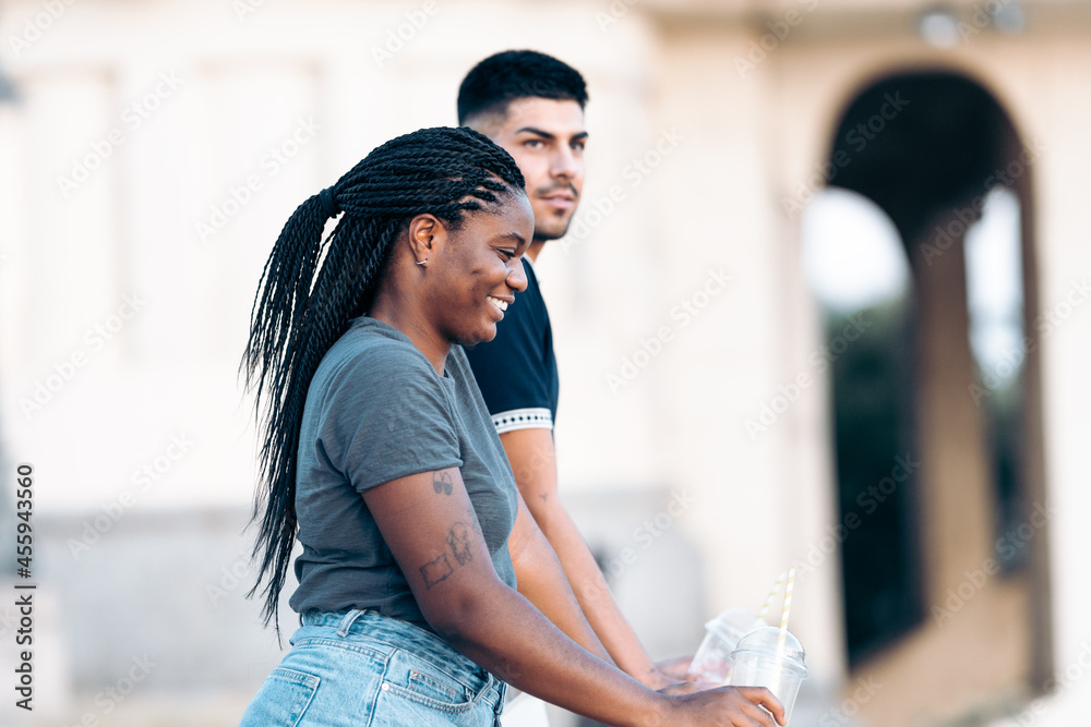 Fototapeta premium Two people of different races leaning on a railing in the street