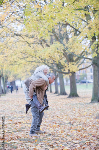 Senior man carrying woman on his back in autumn park © KOTO