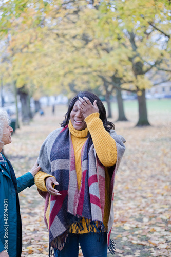 Enthusiastic senior women friends talking and smiling in autumn park