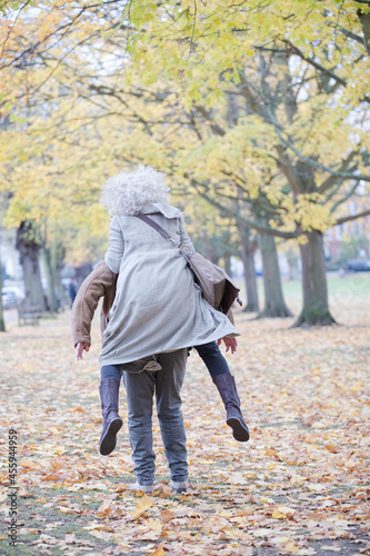 Senior man carrying woman on his back in autumn park © KOTO
