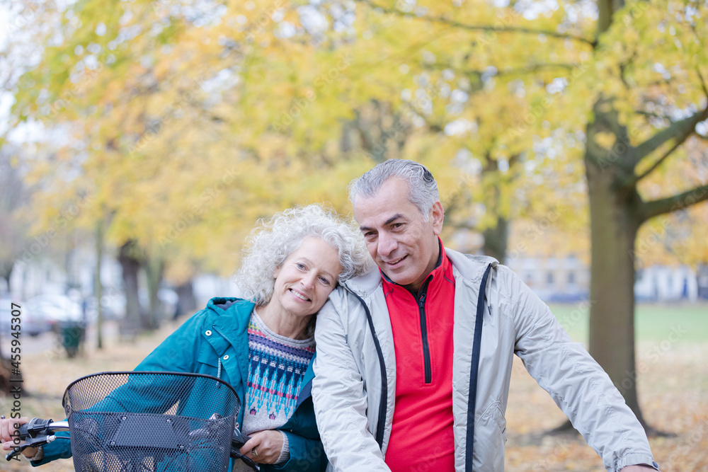 Senior couple walking bicycles among trees and leaves in autumn park Senior couple walking bicycles among trees and leaves in autumn park