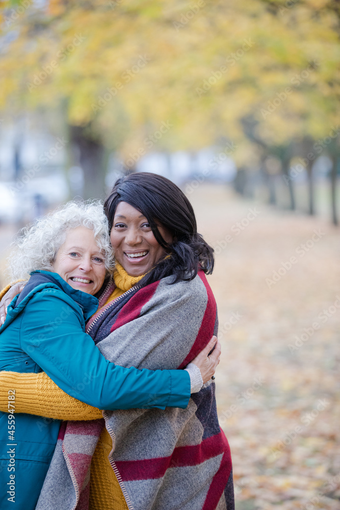 Fototapeta premium Enthusiastic senior women friends hugging in autumn park
