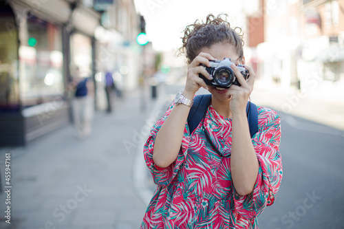 Portrait laughing, enthusiastic young female tourist in sunglasses photographing with camera on urban street © KOTO