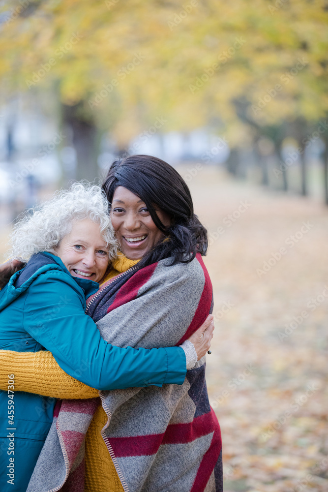 Fototapeta premium Enthusiastic senior women friends hugging in autumn park