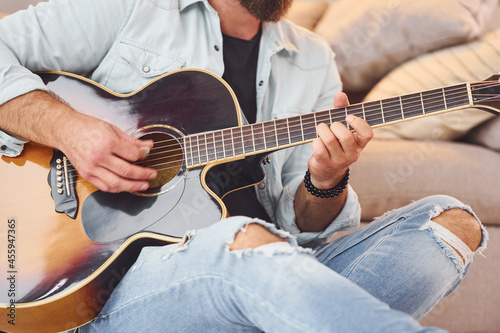 Cozy atmosphere. Man in casual clothes and with acoustic guitar is indoors