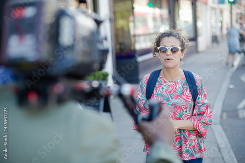 Enthusiastic young woman posing for video camera on urban street