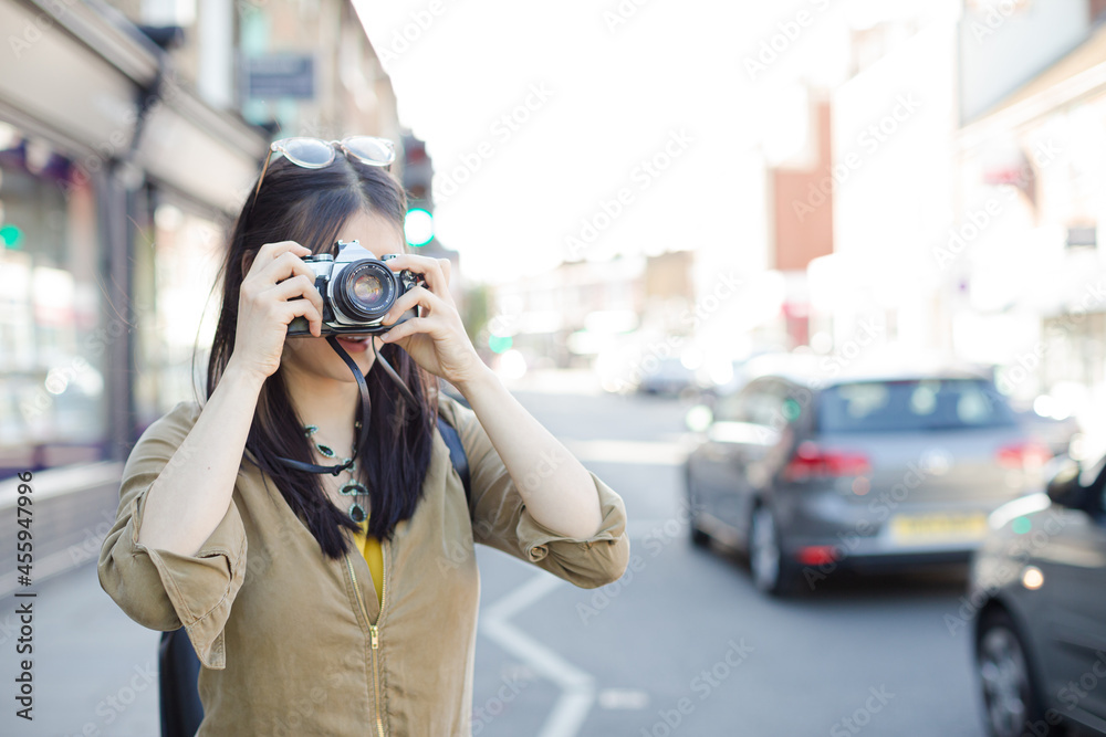 Smiling young female tourist photographing with camera on urban street Smiling young female tourist photographing with camera on urban street