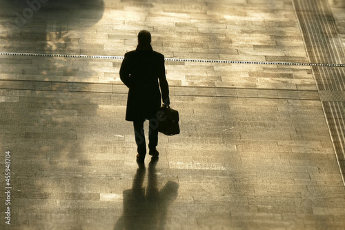 Silhouette of the lonely man with a bag walking on the street. photo