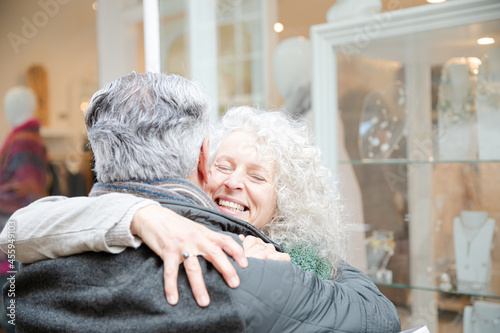 Senior couple hugging, window shopping at jewelry storefront