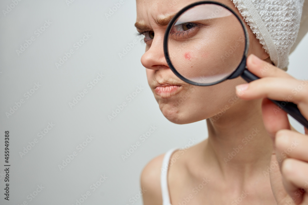 pretty woman with a magnifying glass in hand skin problems close-up pretty woman with a magnifying glass in hand skin problems close-up
