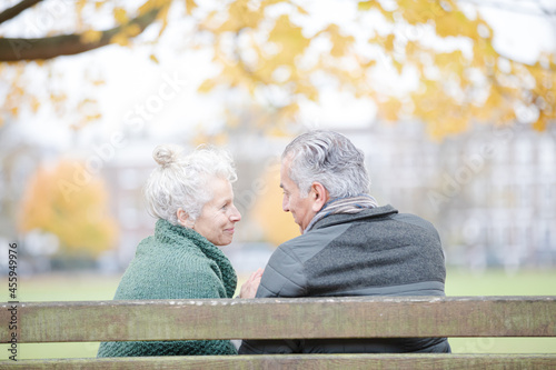 Affectionate senior couple sitting on bench in autumn park © KOTO