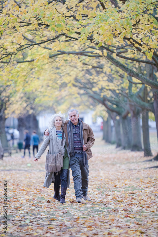 Obraz premium Affectionate couple hugging, walking among trees and leaves in autumn park