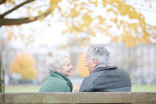 Affectionate senior couple sitting on bench in autumn park © KOTO