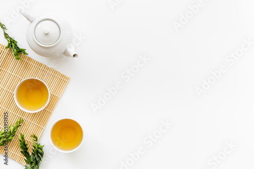 Black tea in cups with white teapot and green leaves