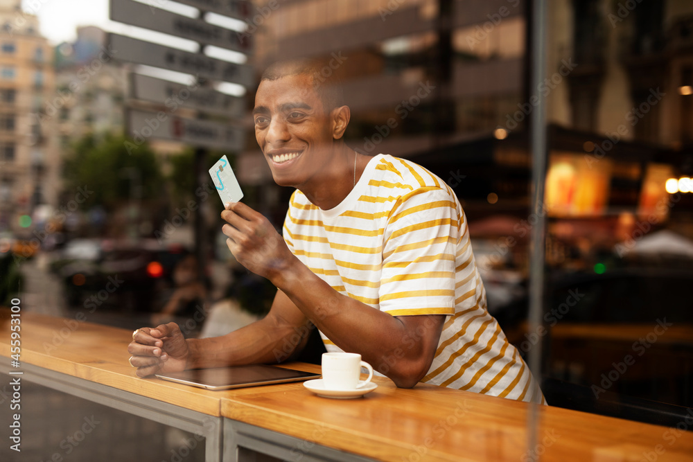 Handsome young african man in cafe drinking coffee. Portrait of happy man with credit card drinking coffee in cafe. Handsome young african man in cafe drinking coffee. Portrait of happy man with credit card drinking coffee in cafe.
