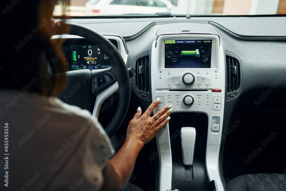 Close up view of front control panel. Woman in casual clothes is sitting in her automobile at daytime Close up view of front control panel. Woman in casual clothes is sitting in her automobile at daytime