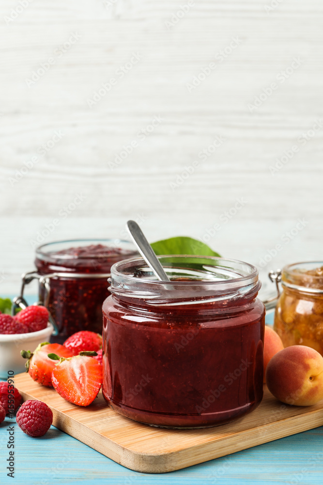 Jars with different jams and fresh fruits on light blue wooden table Jars with different jams and fresh fruits on light blue wooden table