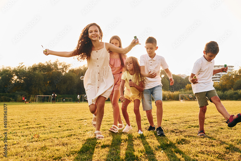 Standing on the sportive field. Group of happy kids is outdoors at daytime Standing on the sportive field. Group of happy kids is outdoors at daytime