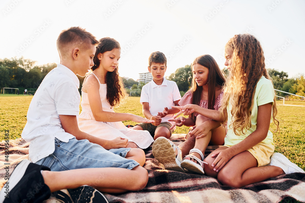 Fototapeta premium Communicating with each other. Group of happy kids is outdoors on the sportive field at daytime