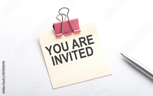 YOU ARE INVITED text on sticker with pen on the white background