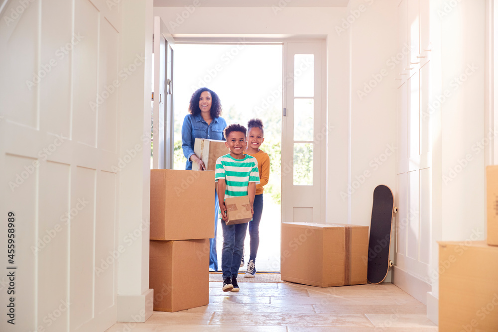 Children Helping Mother To Carry Boxes Into New Home On Moving In Day