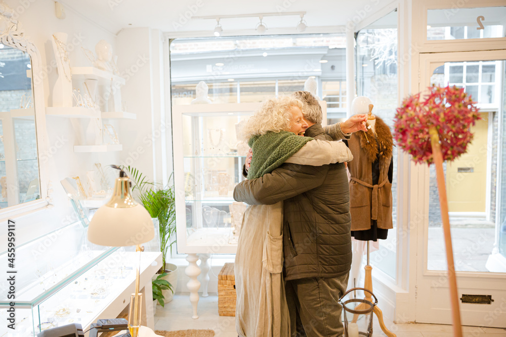 Happy senior woman hugging husband in jewelry store Happy senior woman hugging husband in jewelry store