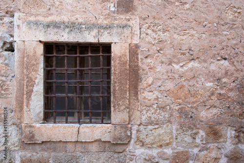 old window with bars, located in a medieval wall © pintoreduardo