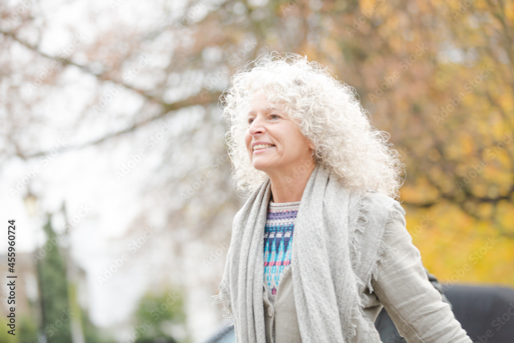 Thoughtful senior woman looking up at autumn trees in park Thoughtful senior woman looking up at autumn trees in park