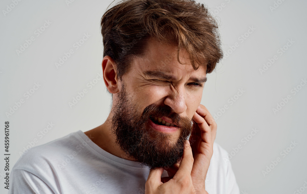 bearded man holding his face toothache