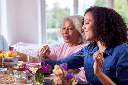 Mother And Adult Daughter Enjoying Multi-Generation Family Meal At Home
