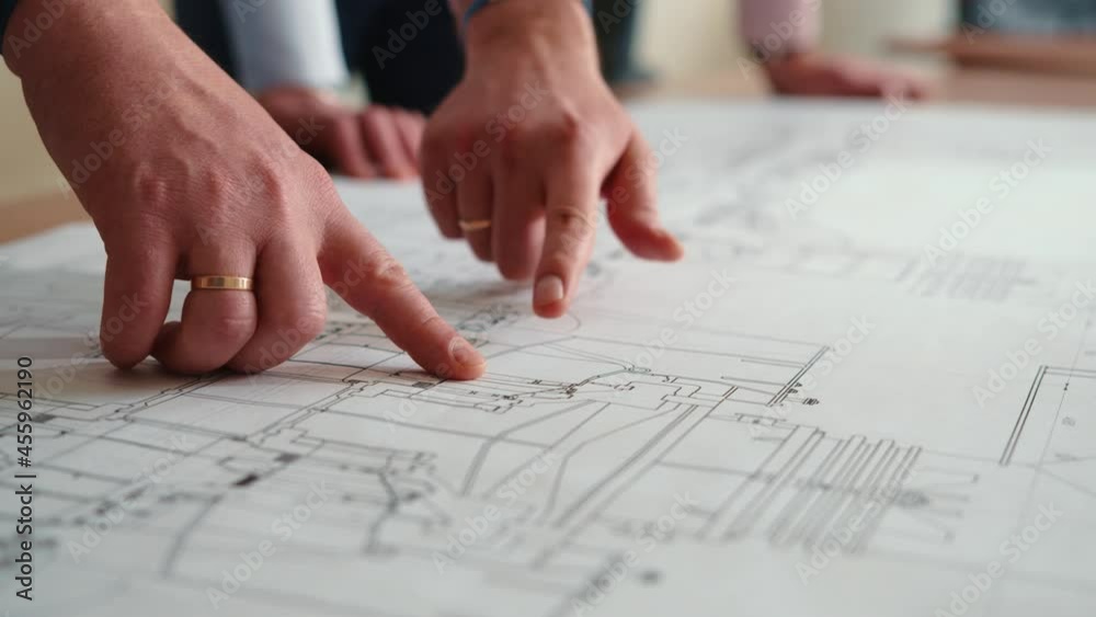 Hands engineers in shot on drawing table. They point their fingers at the blueprint. Engineers team discussing together with blueprint on the drawing table for planning the work in the industrial Hands engineers in shot on drawing table. They point their fingers at the blueprint. Engineers team discussing together with blueprint on the drawing table for planning the work in the industrial