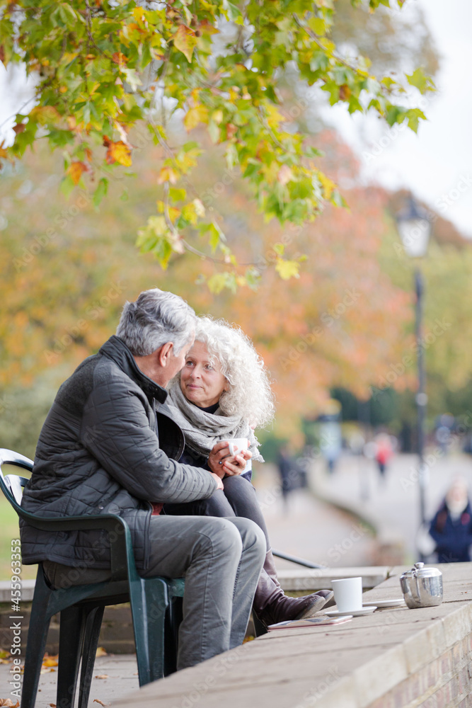 Active senior couple talking, enjoying coffee at autumn park cafe Active senior couple talking, enjoying coffee at autumn park cafe