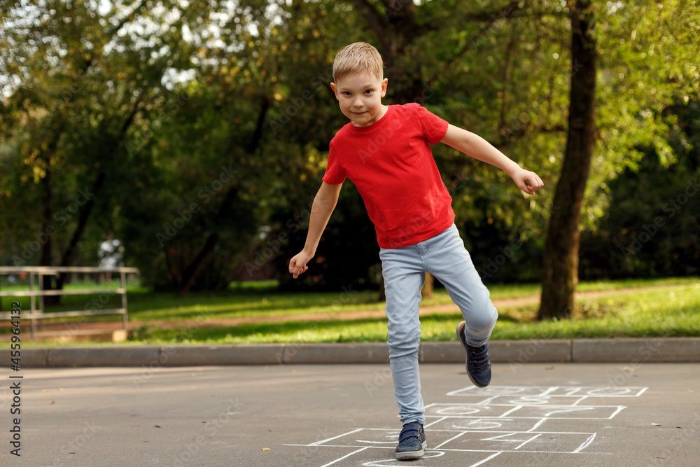 Cute little boy playing hopscotch outdoor. Street children's games. Selective focus.
