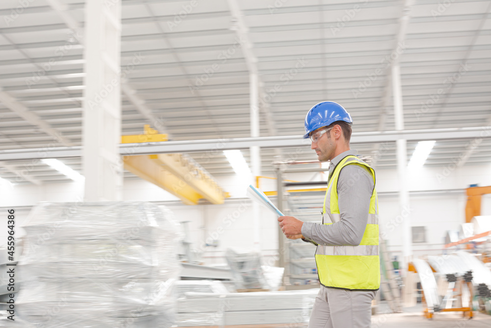 Male supervisor with paperwork walking in factory Male supervisor with paperwork walking in factory