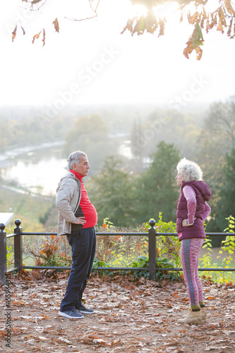 Affectionate active senior couple doing exercise at autumn park
