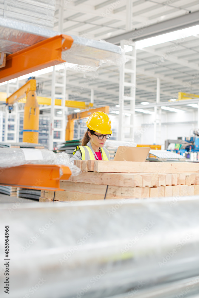 Female worker using laptop in factory Female worker using laptop in factory