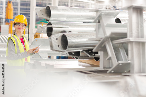 Confident, smiling female worker using digital tablet in factory
