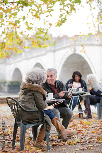 Senior couple using digital tablet, enjoying coffee and tea at autumn park © KOTO
