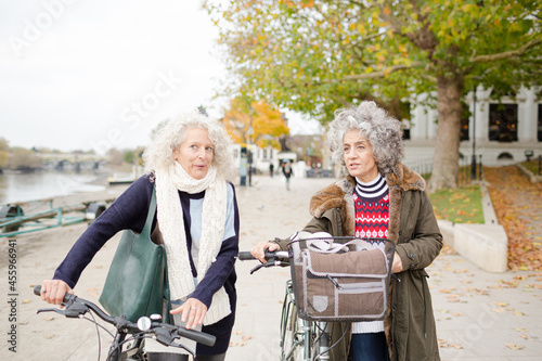 Smiling active senior women walking bicycles in autumn park © KOTO